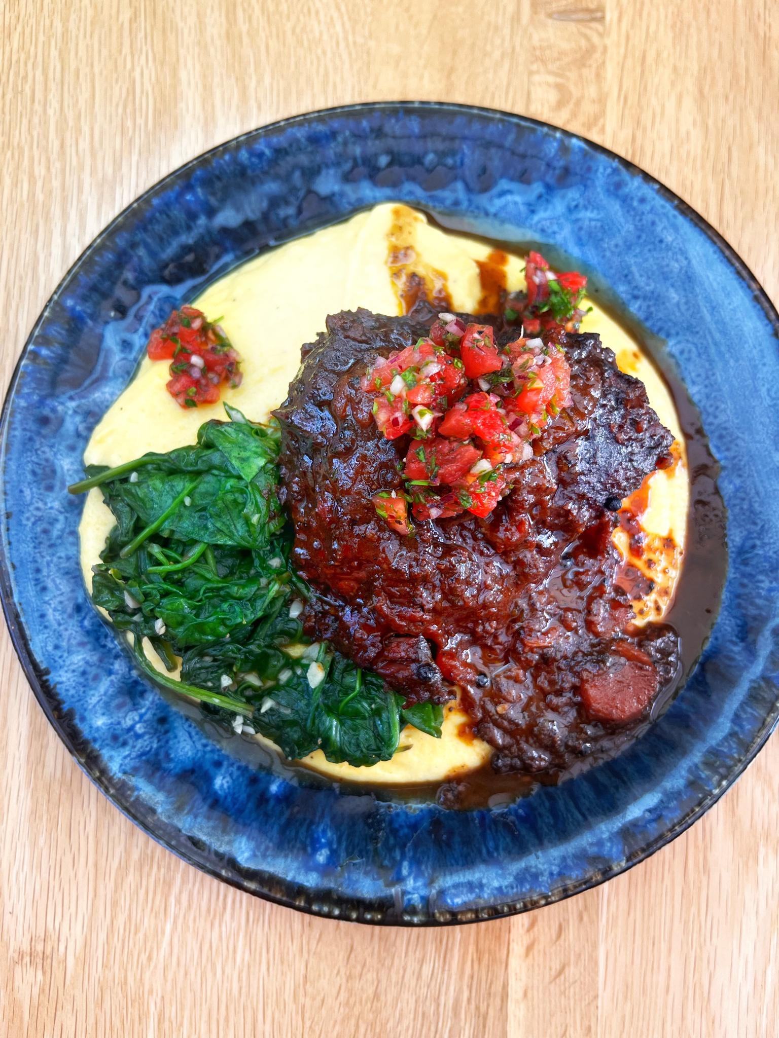 Braised Oxcheek in pink wine on cheddar cheese polenta with garlic spinach and a rough chopped salsa for freshness