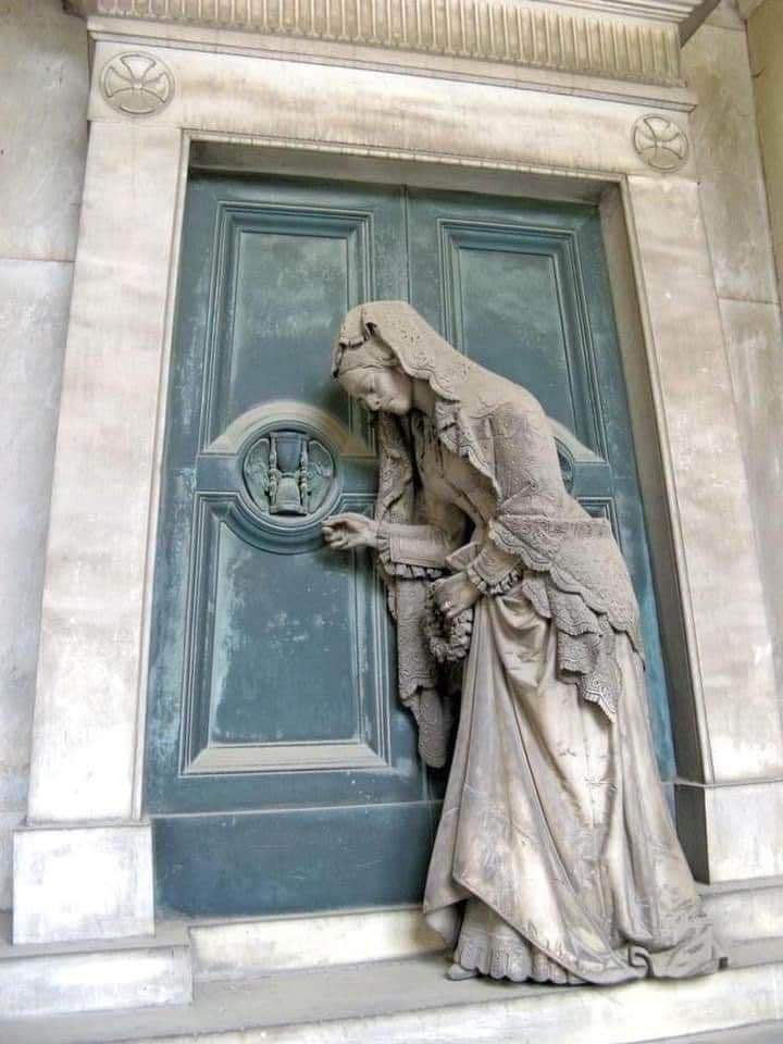 Sculpture of a girl knocking on a door from the tomb of Pietro Badaracco in Staglieno Cemetery by G.B. Cevasco/1876.