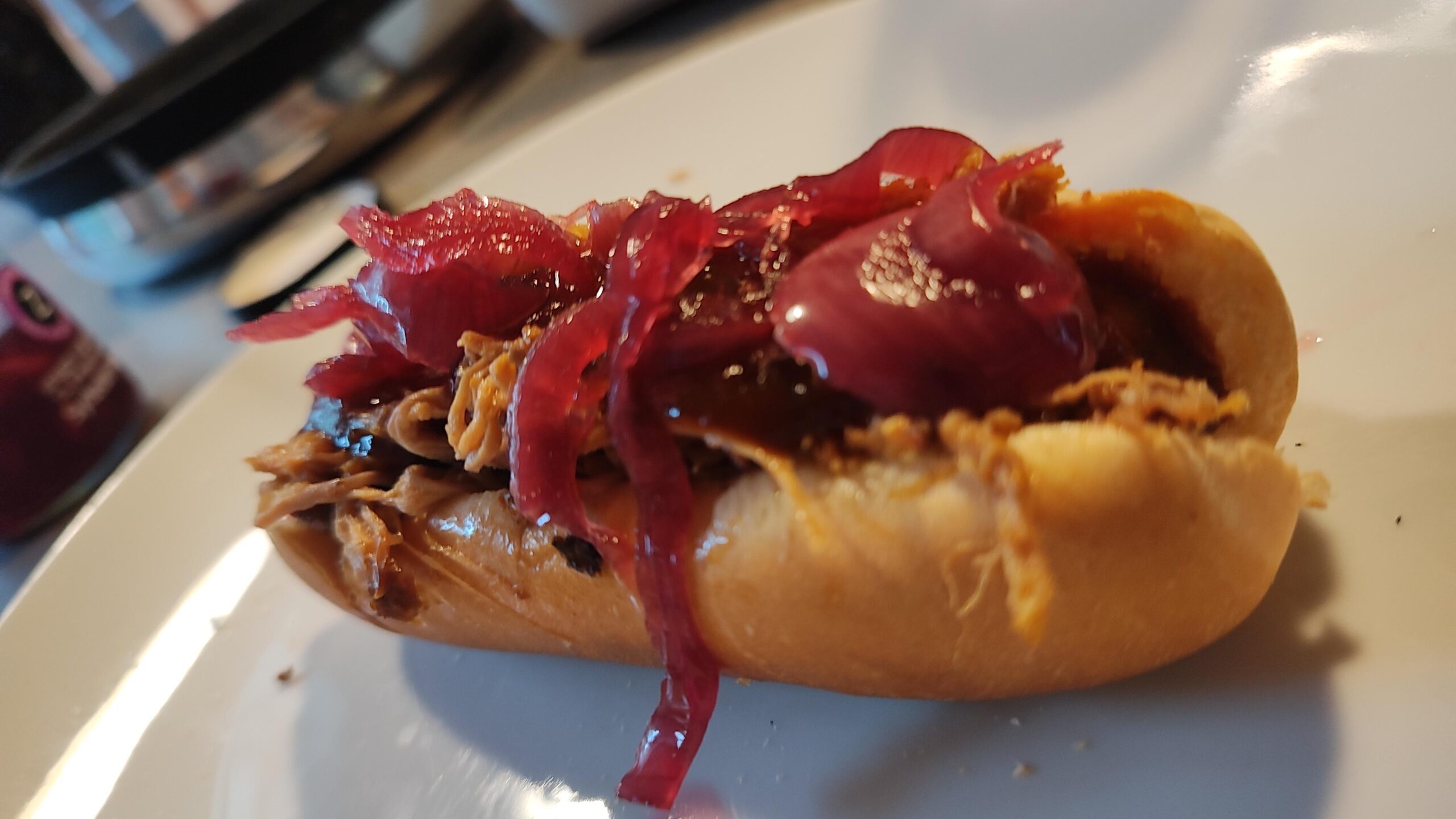 Pulled pork dog with barbecue sauce and picked pink onions